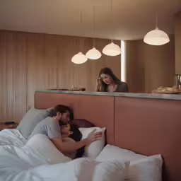a couple in bed as a woman takes a picture of them