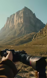 a man holding a camera taking pictures in the mountains