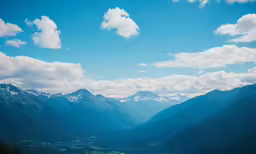 a panoramic view of mountains and water with clouds