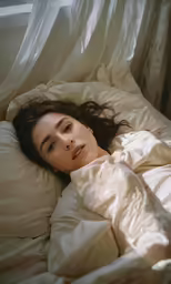 a woman laying in bed under a blanket