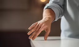 a person in a blue shirt reaching towards a white counter