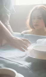 a girl has her arm wrapped around a teacup while someone places their finger on top of the plate
