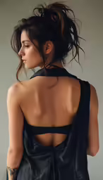 a model in a black dress with a tattoo on her back