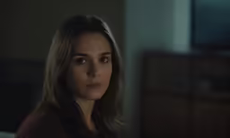 a woman looking down at the camera in a dimly lit room
