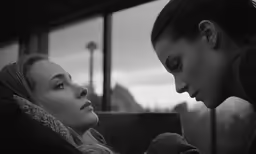 two woman are sitting on a bus looking at something