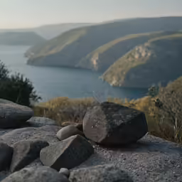 a rock is sitting on the edge of a cliff looking out at a lake