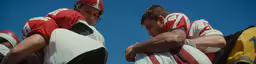two guys wearing football jerseys stand next to each other