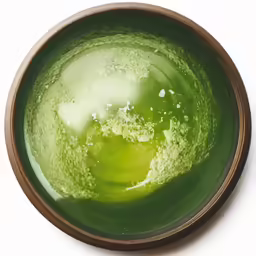 a bowl filled with green liquid sitting on top of a table