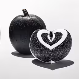 two black apple shaped objects with white decoration on them