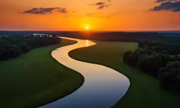 the sun is setting on a river as seen from an airplane