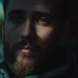 a bearded man is wearing a scarf and looking at the camera