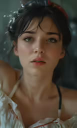 a woman with dark hair wearing white and a red necklace