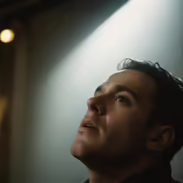 a man is looking up in a dimly lit room