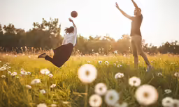 a man and woman jumping up to catch a ball
