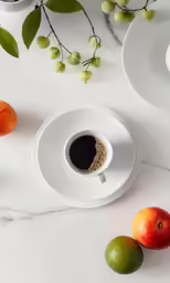an assortment of fruit is arranged around two cups of coffee