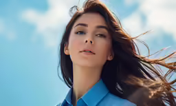 woman with flying hair on blue shirt looking upward