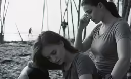 two beautiful women sitting down on the beach
