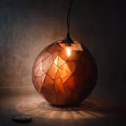 an orange light bulb in a brown mosaic print shade