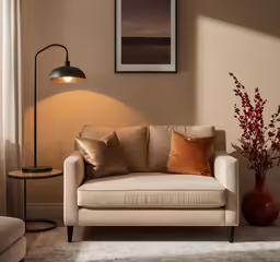 there is a couch with pillows, a lamp, and a vase in front