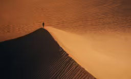 the two people walk through the sand dunes in the sahara