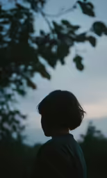 a woman is standing in the park under a tree