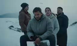 four people standing around talking on a mountain side