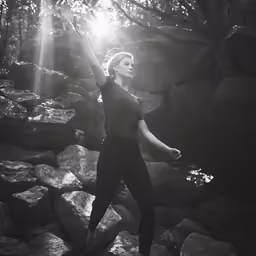 a woman is standing on rocks while holding up her arm
