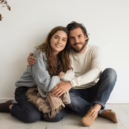 couple sitting in front of wall posing for camera