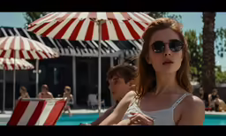 there are two women standing by the swimming pool