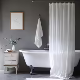 a bathroom has a large bathtub, white shower curtain and black and white rugs