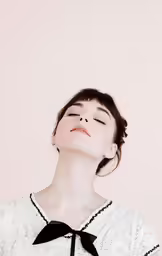 a young woman with a black and white dress and eyes closed, wearing a neck tie