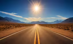 the sun shines brightly over an empty desert road
