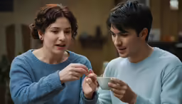 a young man and woman are looking at something in their hands