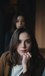 a woman wearing a cardigan in front of another person