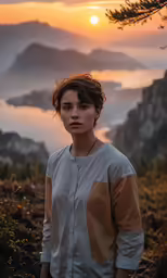 a woman standing in the grass near a lake with mountains and mists
