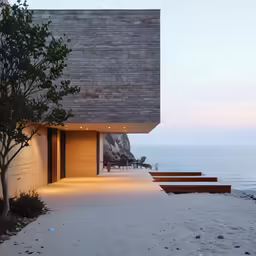 a stone building with concrete steps and a small tree near the water