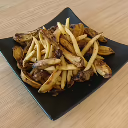 black plate with french fries on it, on top of wooden table