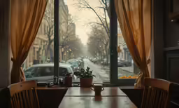 an empty wooden dining room table in front of an open window overlooking the street
