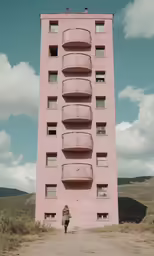the woman is standing near a building that looks like it has balconies on top