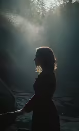 a woman with her hands on the wrist under sunlight shining through the leaves and rocks