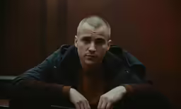 a man leaning his elbows on his lap in front of the camera