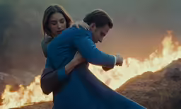 a man and a woman embracing while standing in front of fire