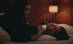 two women laying on a bed in the dark