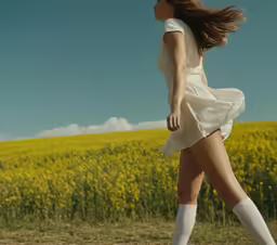 woman in white dress and white knee socks running across field