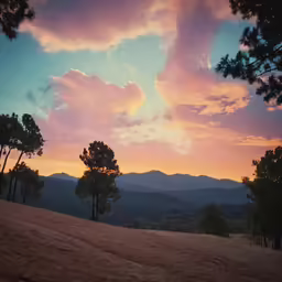 the sun setting on top of the mountain and some trees