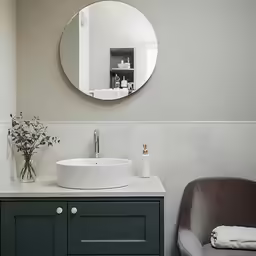 a sink in front of a mirror with a chair and table