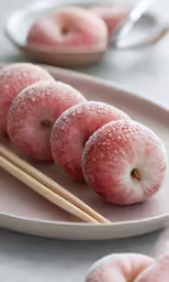 three peachs and chopsticks are on a plate