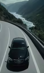 a car driving down a mountain road with mountains in the background