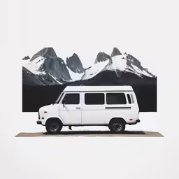a large white van parked in front of some snow covered mountains