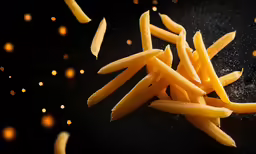 a black surface with french fries cut in half